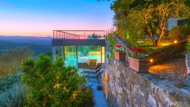 A modern glass house with a balcony overlooking a scenic landscape. - Villa Antico Incanto (Monte Castello di Vibio)