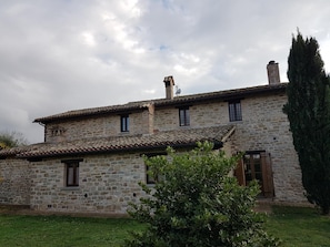 A stone building with a tiled roof, a chimney, and a small window. - Villa Cardellini (Gubbio)