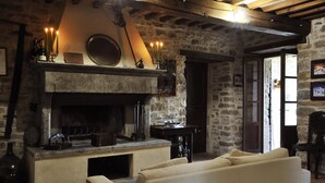 Un intérieur rustique en pierre, avec une cheminée, des bougies et un canapé.
