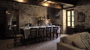 Un coin repas rustique avec un mur en pierre, des poutres en bois et une table dressée pour six personnes.