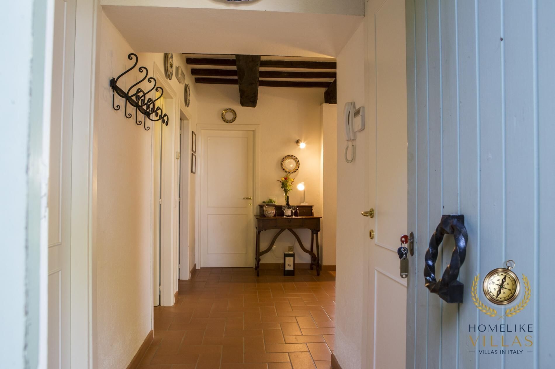 Un couloir doté d  ’un sol carrelé, d’une porte en bois et d’un luminaire fixé au mur.