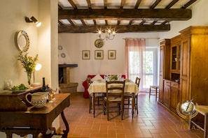 A rustic dining area with a wooden table set for four, a fireplace, and a wooden cabinet.