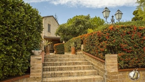 A stone staircase leading to a building with a traditional design, surrounded by lush greenery and vibrant flowers. - Villa Anna (Giulianova)
