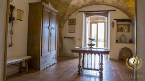 A room with a wooden cabinet, a bench, a table with a decorative bowl, and a large window with a view. - Villa Anna (Giulianova)