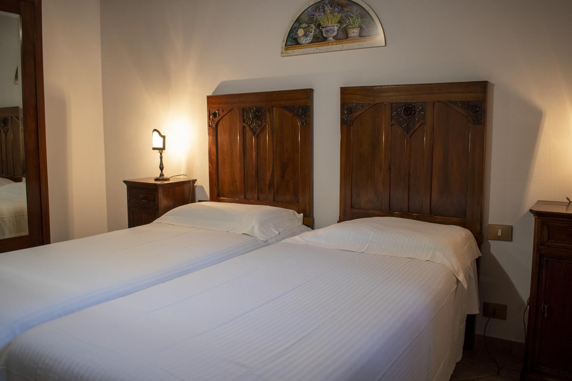 Un dormitorio con dos camas de madera, una mesita de noche con lámpara y un adorno en la pared sobre las camas.