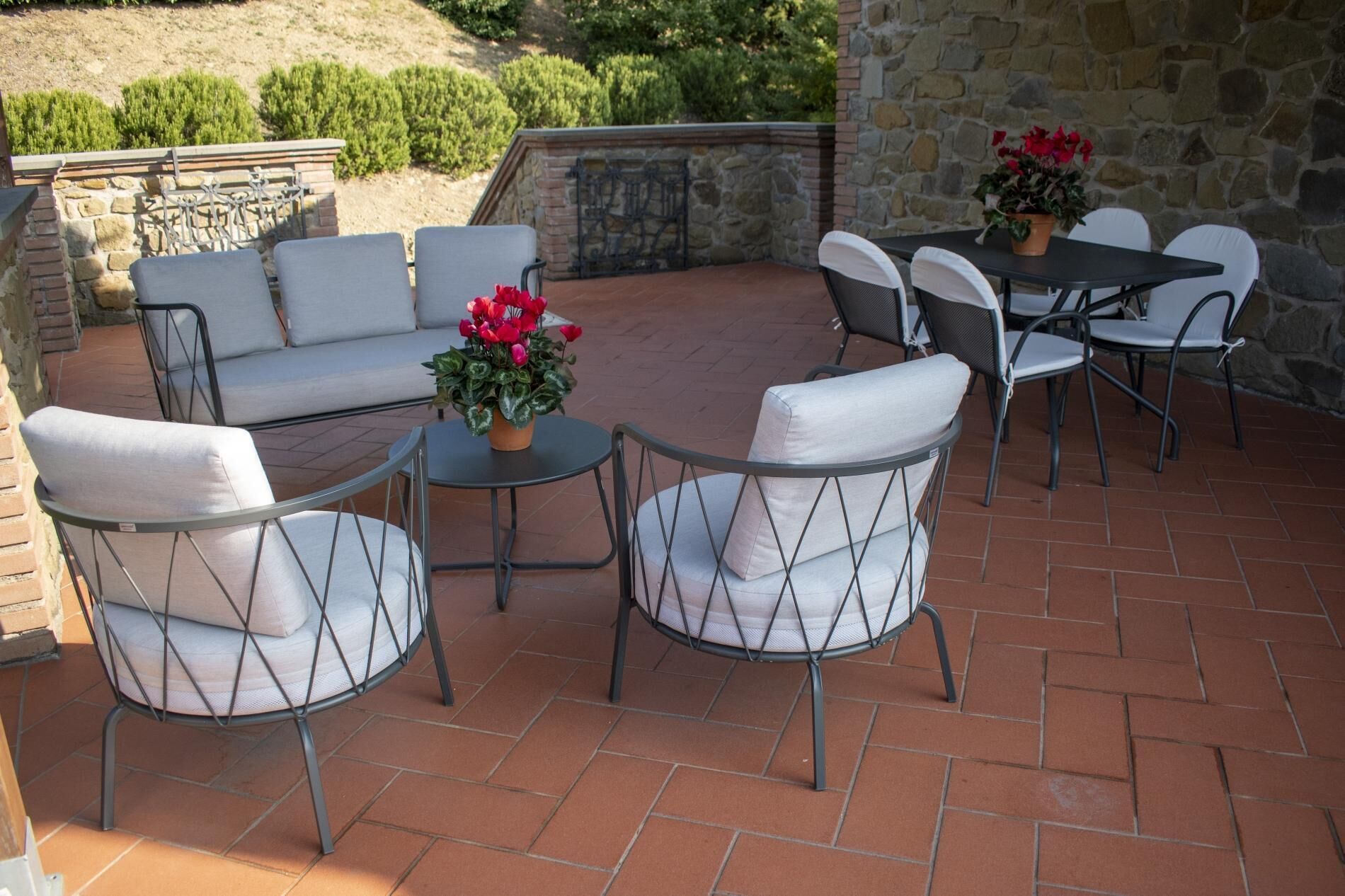 An outdoor patio with a stone wall, a sofa, and a table surrounded by chairs.