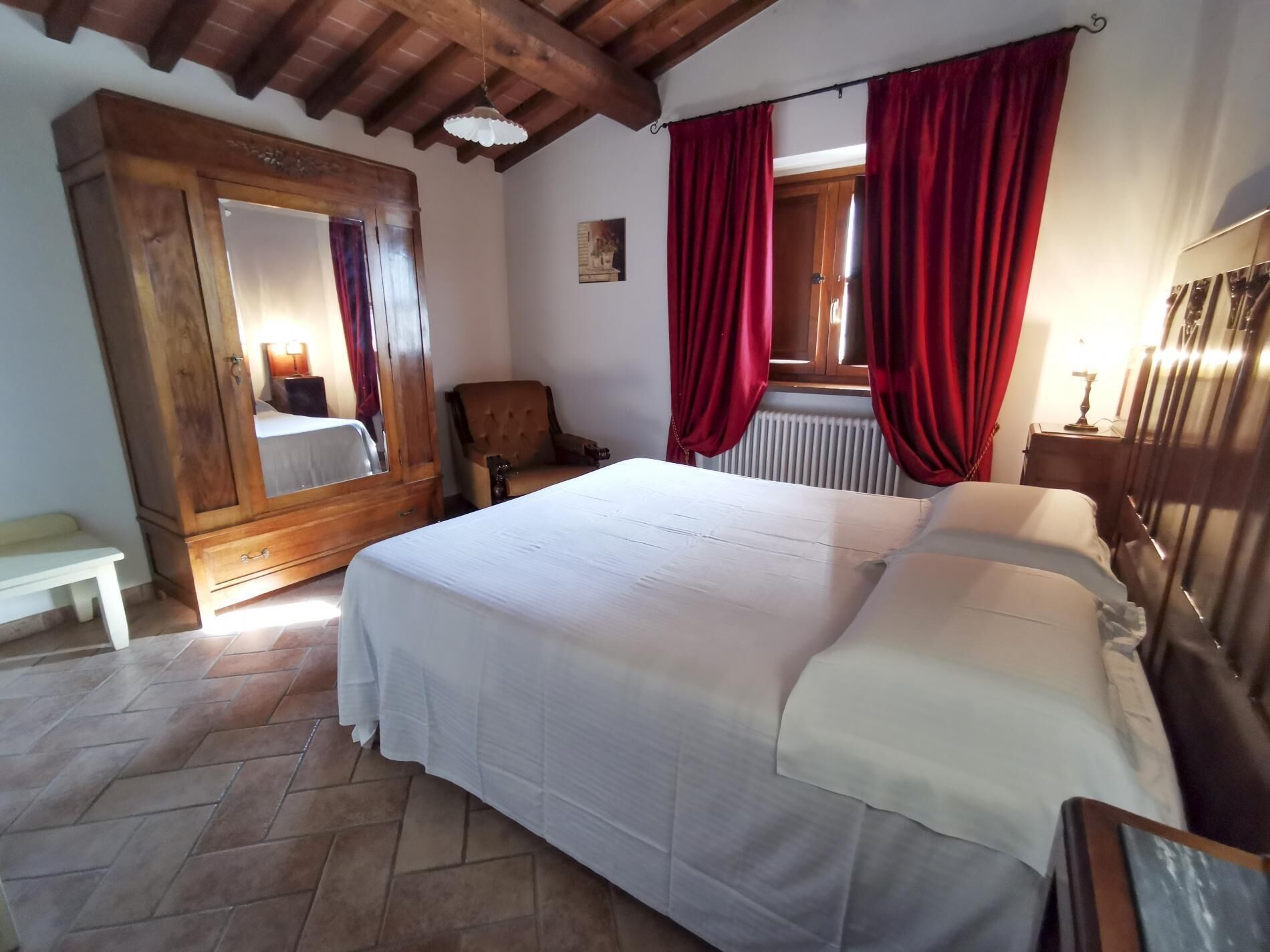 Een slaapkamer met een groot bed, een houten garderobe en een stoel.