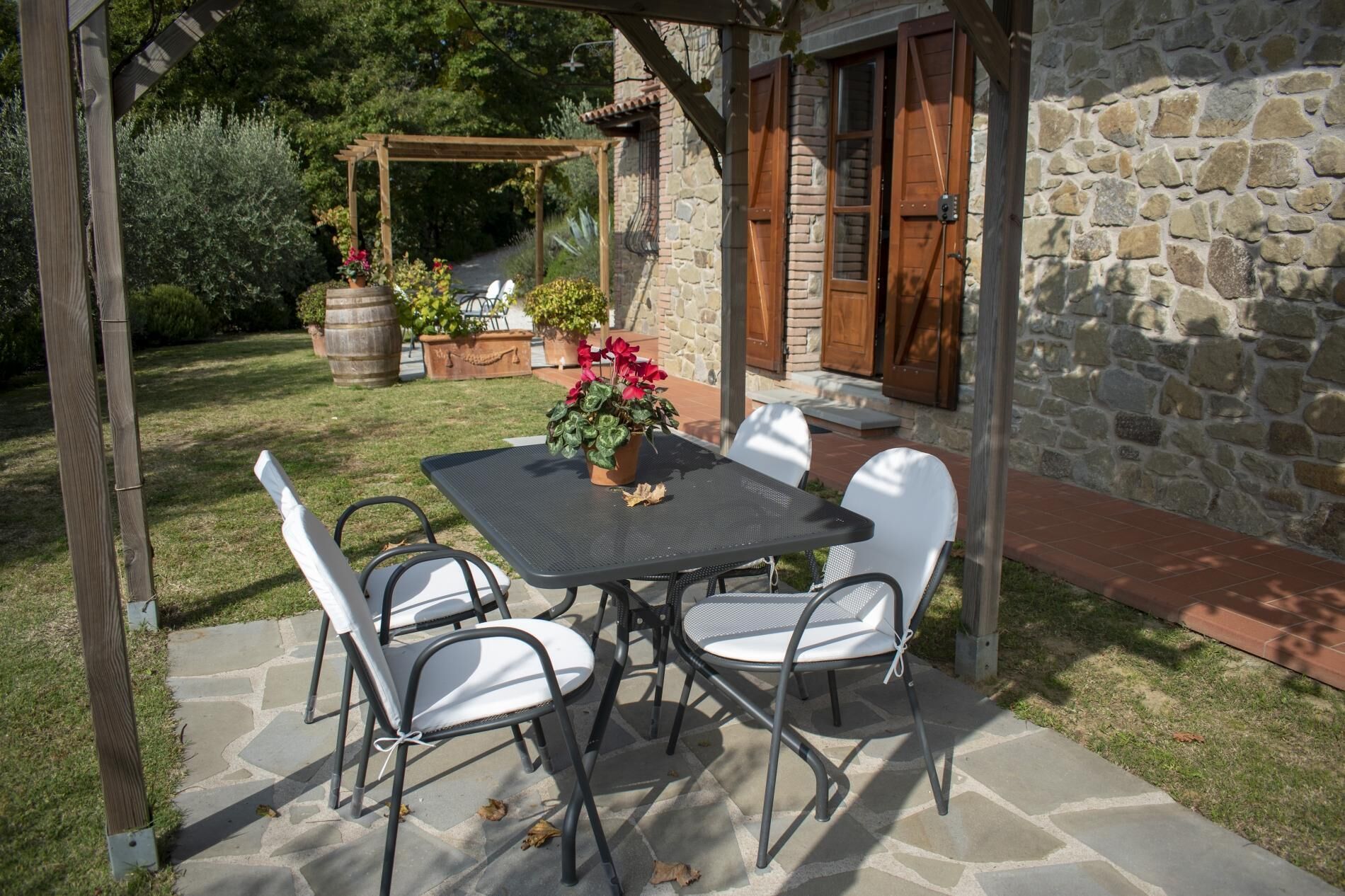 An outdoor patio with a table and chairs, surrounded by stone walls and potted plants.