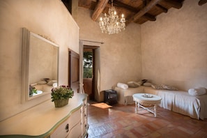 A cozy bedroom with a large mirror, a dresser, a bed with pillows, a small table, and a chandelier.
