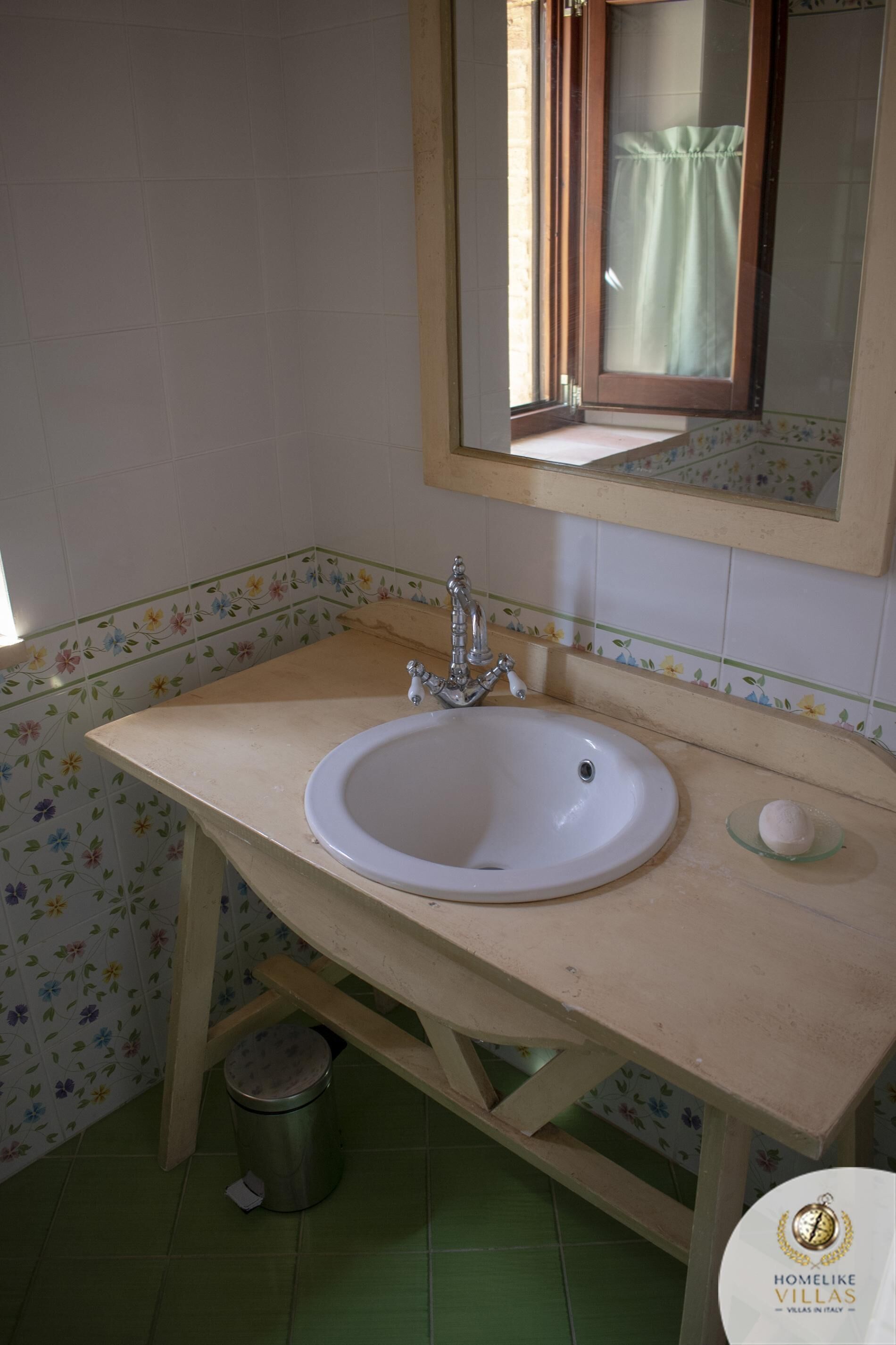 Une salle de bain avec un lavabo blanc, un miroir et une poubelle.