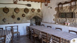 A rustic dining area with a stone wall, wooden beams, and a tiled floor. - Villa Claudia (Gualdo)