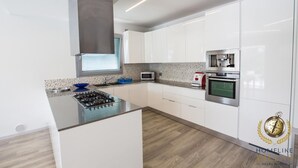 A modern kitchen with white cabinets, a gas stove, a microwave, and a built-in oven. - Villa Giorgi (Cingoli)