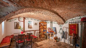 Un coin repas rustique avec un plafond en briques, des meubles en bois et un tableau accroché au mur.