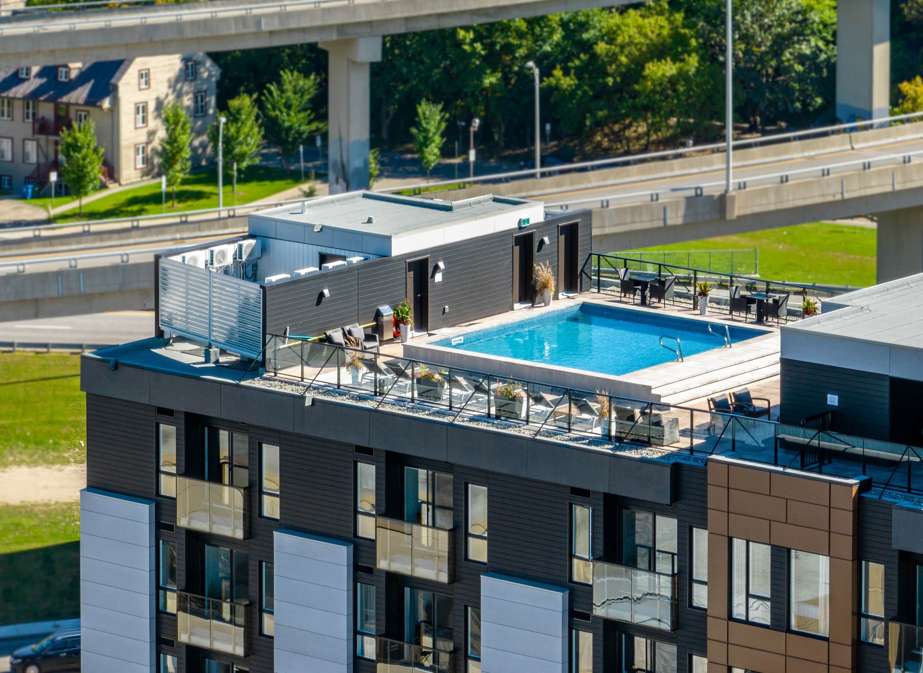A rooftop pool with lounge chairs and a view of a bridge.