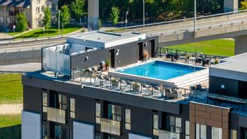 A rooftop pool with lounge chairs and a view of a bridge.