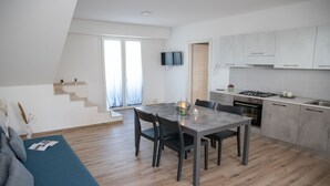 Eine moderne Küche mit Essbereich, Holzboden und einer Treppe, die auf einen Balkon führt.