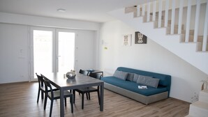 Ein zeitgemäßer Wohnbereich mit Essplatz, einer Couch und einer Treppe.
