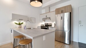 Een moderne keuken met een centraal eiland, roestvrijstalen apparatuur en houten kastjes.