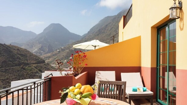 A balcony with a table, chairs, and a wicker basket of fruit. - Home2Book Stunning View La Era2 de Hermigua & Wifi (Hermigua)