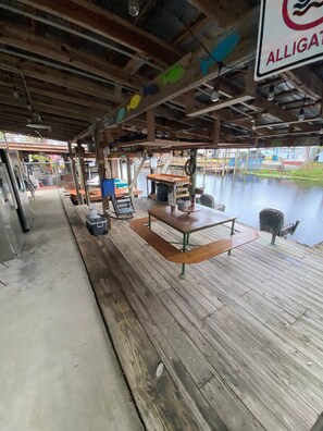 Een houten terras met picknicktafels en banken, met uitzicht op een waterpartij.