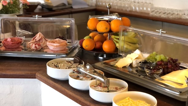 Un bufé con diversas opciones de comida, incluyendo carnes, frutas y quesos.