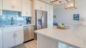 Een moderne keuken met witte kasten, roestvrijstalen apparatuur en een marmeren aanrecht.