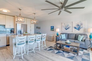 A modern kitchen with white cabinets, a built-in refrigerator, and a dining area with white chairs.