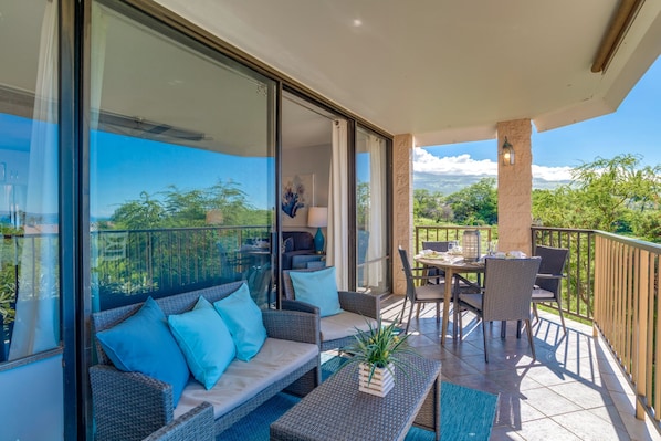 A balcony with a sofa, chairs, and a dining table.