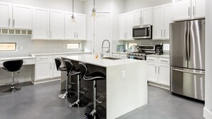 A modern kitchen with white cabinets, stainless steel appliances, and a central island with bar stools.