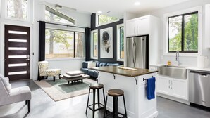 A modern kitchen with a bar area, stainless steel appliances, and a view of the outdoors.
