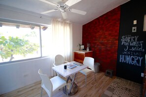 A modern dining area with a white table, chairs, and a ceiling fan. A blackboard with a message is on the wall.