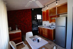 A compact kitchen with wooden cabinets, a refrigerator, a sink, and a dining area with a table and chairs.