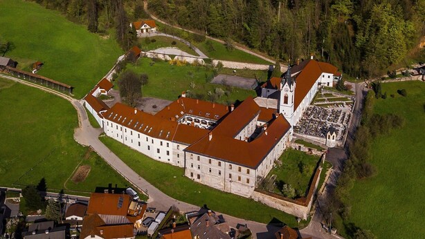 An aerial view of a large, historic building with a prominent tower, surrounded by green fields and a small village. - Hostel Javni Zavod Mekinjski Samostan (Kamnik)
