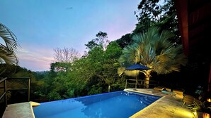 Une piscine à l’eau bleue, entourée de verdure et agrémentée d’un kiosque surmonté d’un toit bleu.