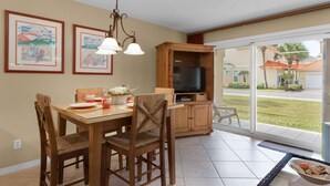 A dining area with a wooden table, chairs, and a TV cabinet.