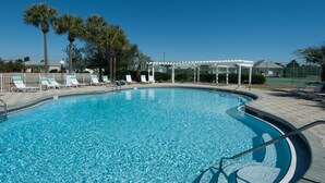 A clear blue swimming pool with lounge chairs and a covered seating area.