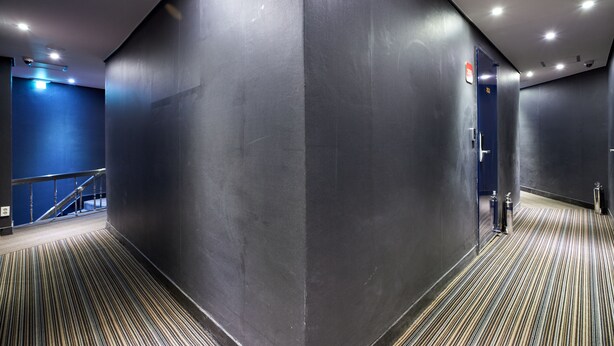 A modern hallway with a striped floor, a blue wall, and a door with a sign. - Hotel Noble Noryangjin (Seoul)