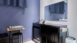 A small, modern bathroom with a sink, mirror, and two stools. - Hotel Noble Noryangjin (Seoul)