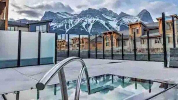 Um hotel moderno com piscina envidraçada e vista para as montanhas.
