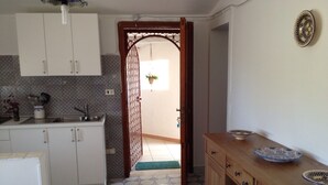 A kitchen with white cabinets, a patterned floor, and a wooden cabinet with a bowl on top.