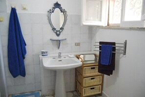 A bathroom with a white sink, a mirror, and a towel rack.