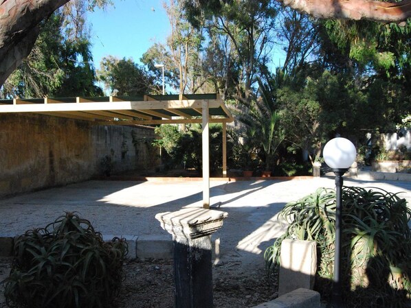 Un espacio al aire libre con una pérgola, un farol y varias plantas.