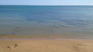 A beach with clear water and a sandy shore.