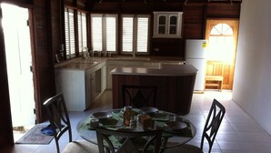 A kitchen with a central island, wooden cabinets, and a dining area with a glass table and chairs. - A spacious rustic house with modern conveniences (St. James)