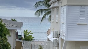 A coastal building with a view of the ocean, a fenced patio area, and a white picket fence. - A spacious rustic house with modern conveniences (St. James)