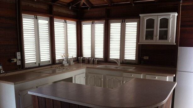 A kitchen with a central island, a sink, and wooden cabinets. - A spacious rustic house with modern conveniences (St. James)