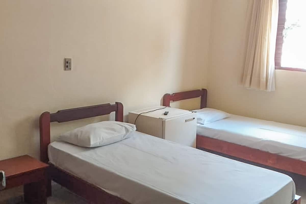 Ein Zimmer mit zwei Einzelbetten, einem kleinen Tisch und einer Steckdose an der Wand.