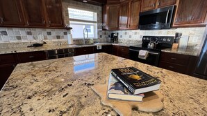 A kitchen with granite countertops, wooden cabinets, a stainless steel refrigerator, and a microwave. - Oceanfront Luxury in small Intimate complex! (West Bay)