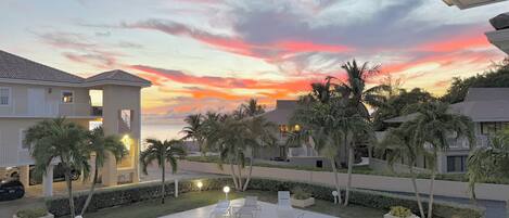 A swimming pool with lounge chairs and a sunset view.
