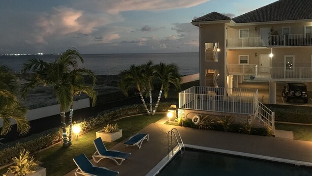 A beachfront hotel with a pool, lounge chairs, and a view of the ocean. - Oceanfront Luxury in small Intimate complex! (West Bay)